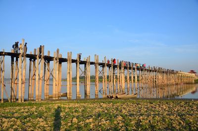 Group of people on wooden pier over lake against sky