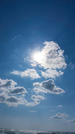 Low angle view of sunlight streaming through clouds