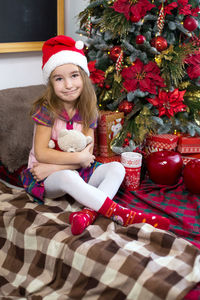 Full length of girl sitting in christmas tree