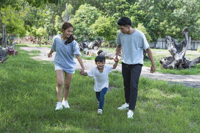 Full length of siblings walking on grassy field