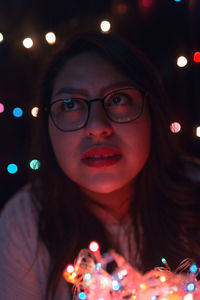 Close-up of young woman with illuminated lights at home