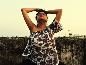 Midsection of woman standing against wall against clear sky