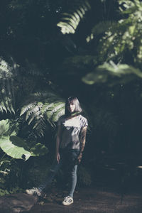 Portrait of young woman standing against trees