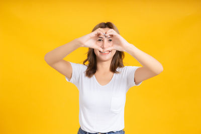 Portrait of smiling young woman against yellow background