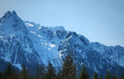 Low angle view of snowcapped mountains against clear blue sky