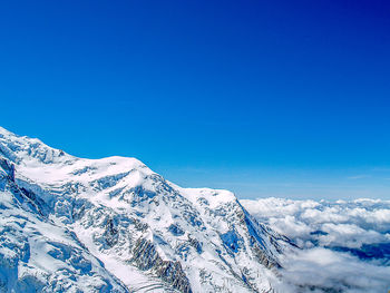 Low angle view of snow against clear blue sky