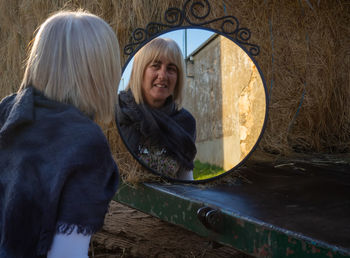 Woman looking into mirror outdoors