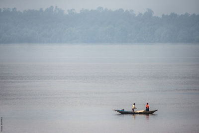 Men in boat on sea against sky