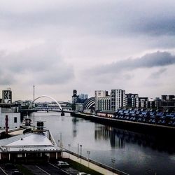 Bridge over river against cloudy sky