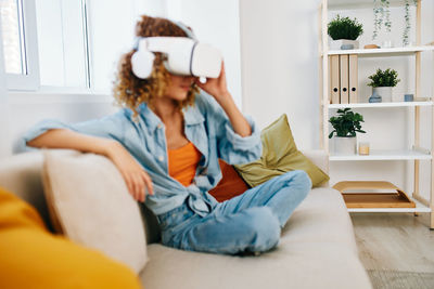 Young woman using phone while sitting on sofa at home