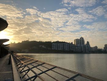 River by buildings against sky during sunset