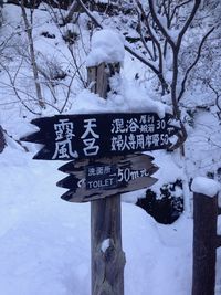 Information sign on snow covered tree against sky