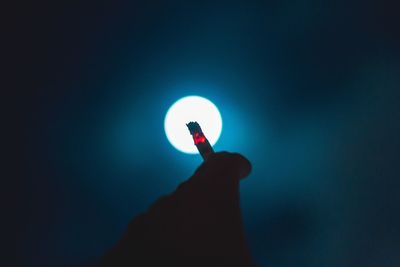 Close-up of hand holding hands against blue sky