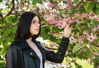 Beautiful young woman standing by flowering plants