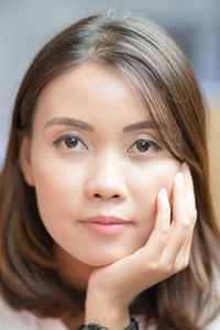 Close-up portrait of mid adult woman with hand on chin