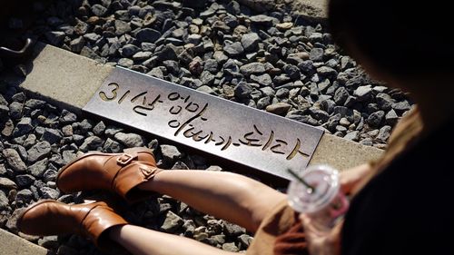 Low section of woman sitting by text on railroad track