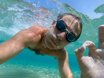 Funny guy having fun and taking underwater selfie while swimming in the sea