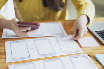 Midsection of man using smart phone on table