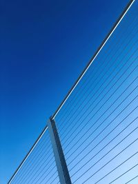 Low angle view of power lines against clear blue sky