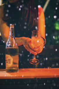 Midsection of woman holding champagne flute on table