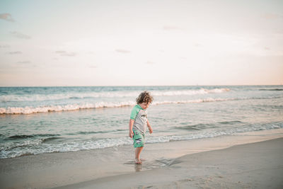 Boy standing on beach against sea