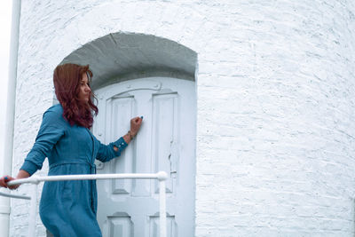 Side view of woman standing against wall