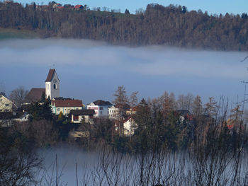 Scenic view of lake by trees and buildings