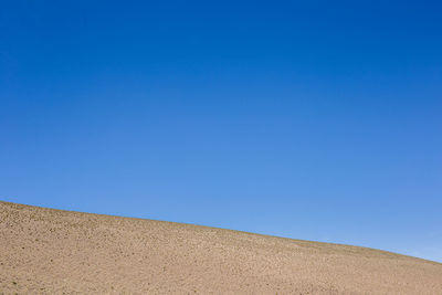 Low angle view of land against clear blue sky