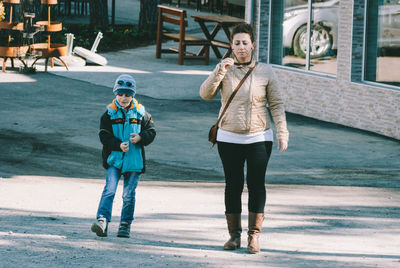 Full length of woman with son walking on road