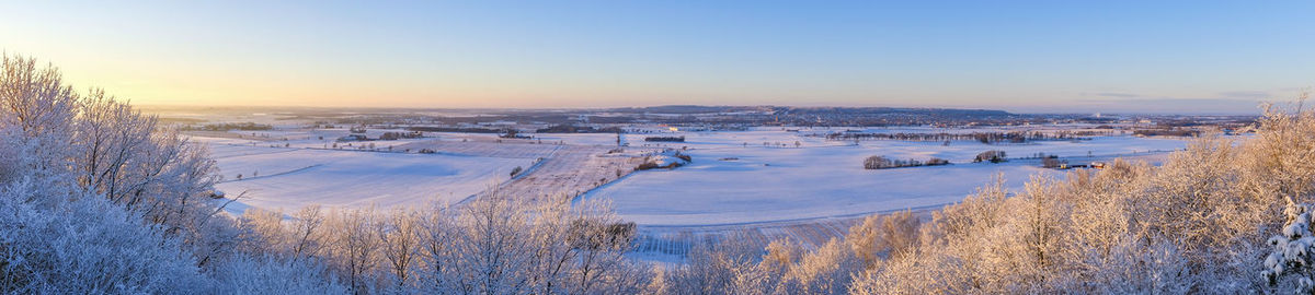 Panoramic view of snow covered land against sky during sunset