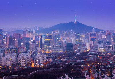 Illuminated buildings in city against sky at night