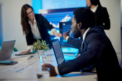 Crop multiracial employees working at table with laptops in office