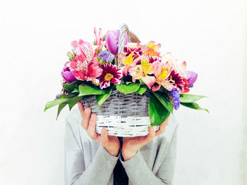 Close-up of person holding bouquet against white background