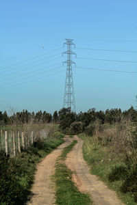 Street amidst field against clear sky