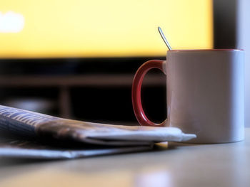 Close-up of coffee cup and newspaper on table