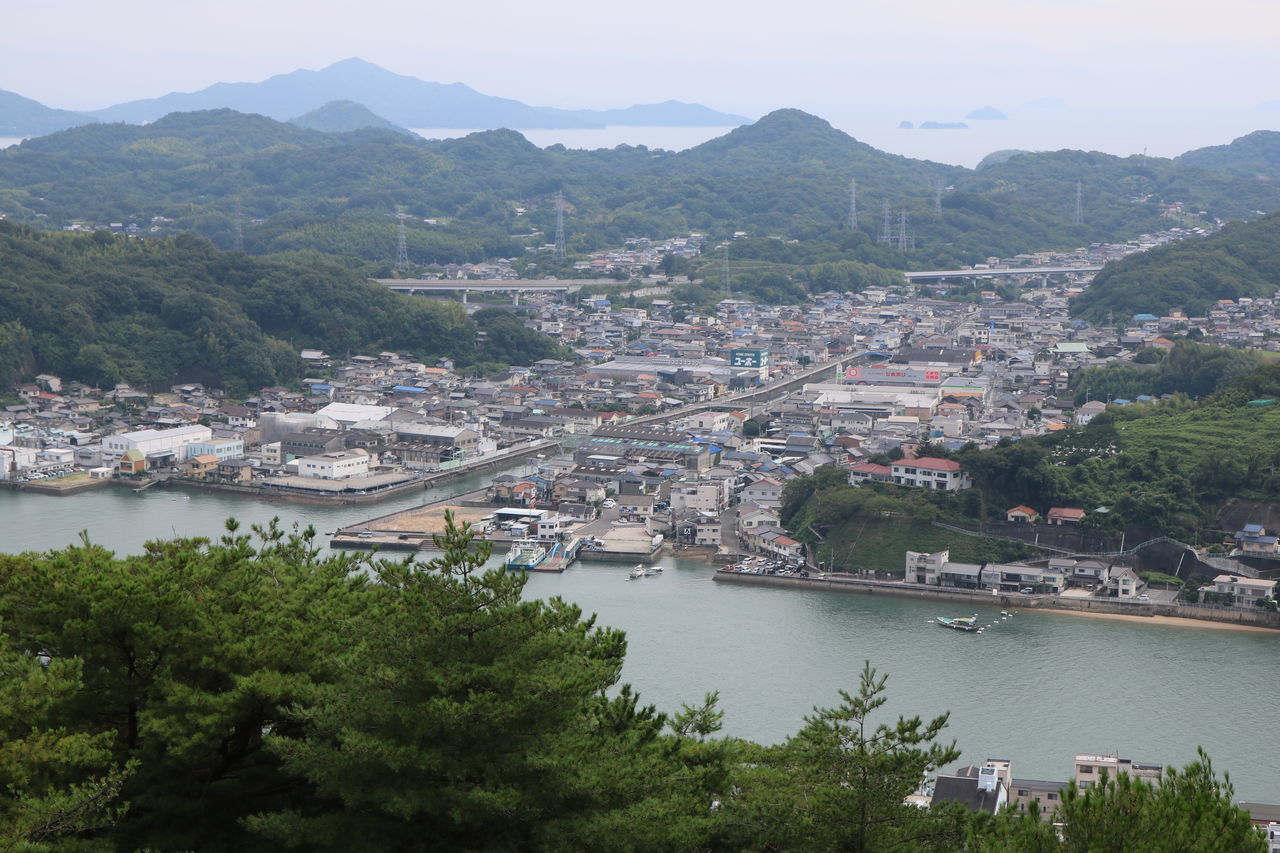 architecture, built structure, tree, building exterior, water, plant, mountain, transportation, city, high angle view, nature, river, no people, day, nautical vessel, sky, beauty in nature, outdoors, mode of transportation, cityscape, townscape