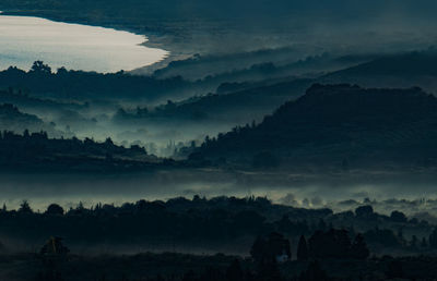 Silhouette trees on landscape against sky