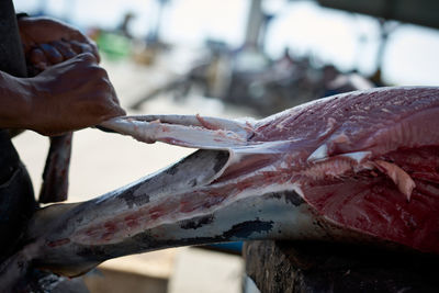 Fish vendor skinning fresh raw tuna fish at seafood market