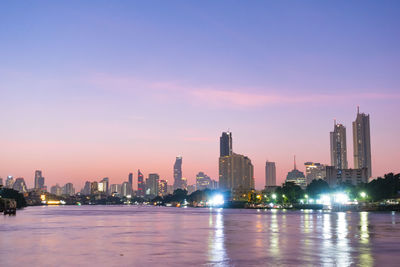 Illuminated buildings in city against sky during sunset