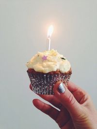 Hand holding cupcake with candle