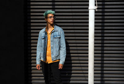 Portrait of young man standing against wall