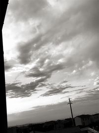 Low angle view of silhouette telephone against sky