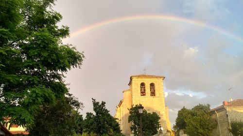 Low angle view of rainbow over building against sky