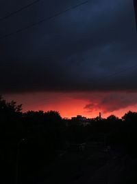 Silhouette trees against dramatic sky during sunset