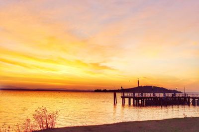 Silhouette pier over sea against sky during sunset