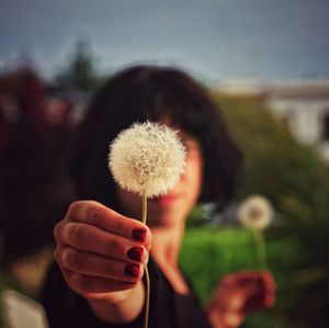 Close-up of woman holding white dandelion