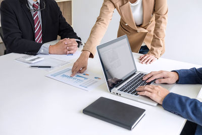 Midsection of woman standing by colleagues showing graph in office