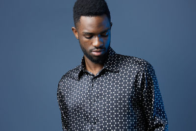 Young man standing against blue background