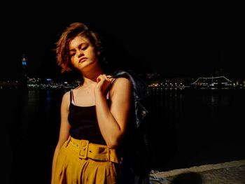 Beautiful young woman looking at illuminated night