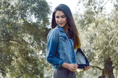 Portrait of smiling young woman standing against trees